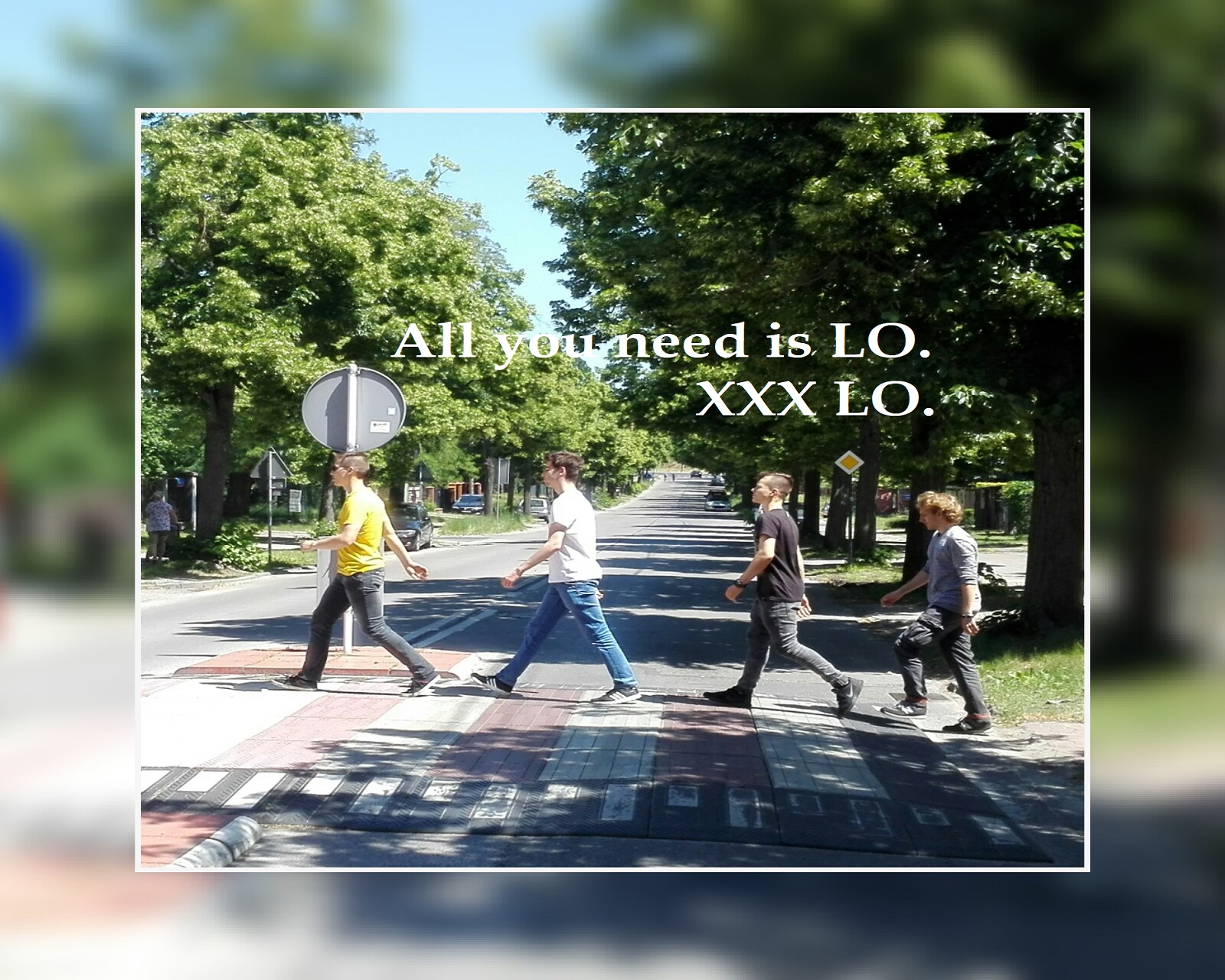 Czworo uczniów przechodzi przez ulicę na przejściu dla pieszych. Idą w prawą stronę. Obrazek inspirowany zdjęciem Beatlesów na Abbey Road